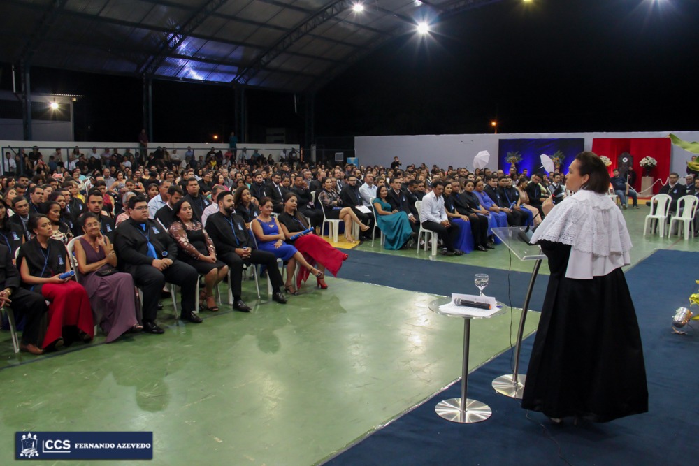 Reitora fala ao microfone para o público presente à coleção de grau na quadra de esportes da uast
