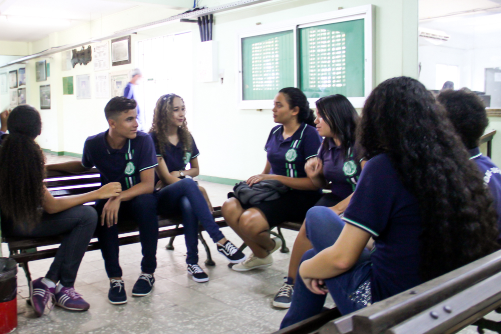 estudantes sentados num banco de madeira. grupo de sete alunos do colégio dom agostinho ikas