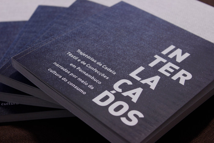 Capa do Livro Interlaçados. Azul, com imagem de tecido jeans e título escrito em letras brancas
