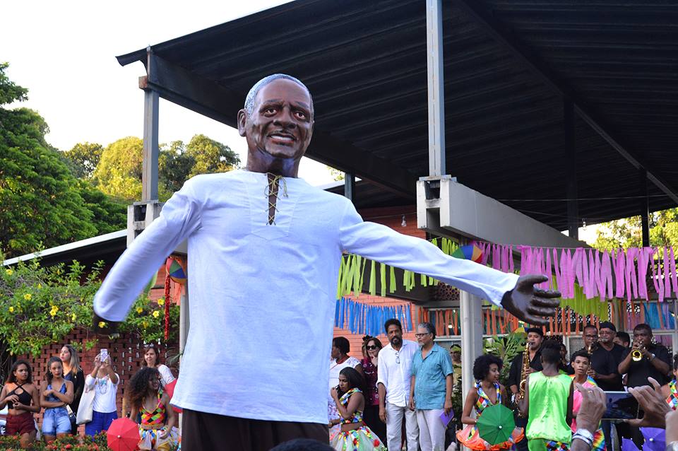 Imagem do boneco gigante de Naná Vasconcelos em frente à Pró-Reitoria de Extensão