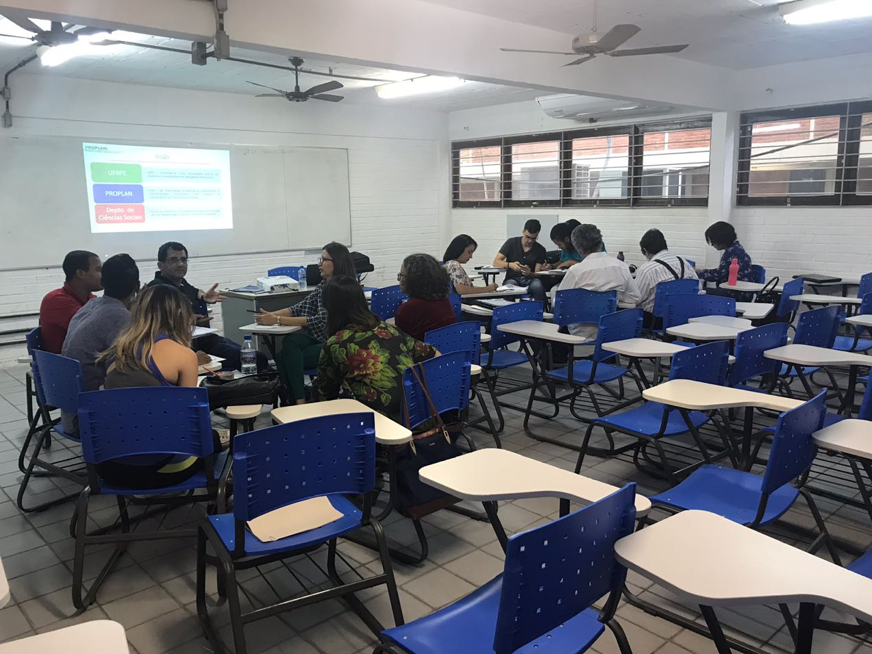 pessoas do departamento de administração sentadas em bancas, dividas em grupo menores