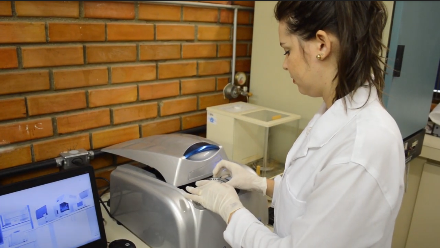 pesquisadora com amostra em equipamento no laboratório