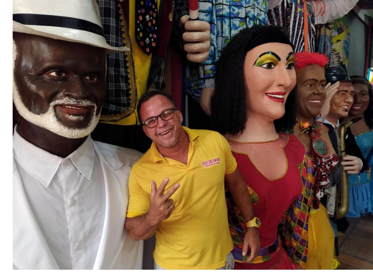 Mestre Camarão em meio aos bonecos gigantes que produz