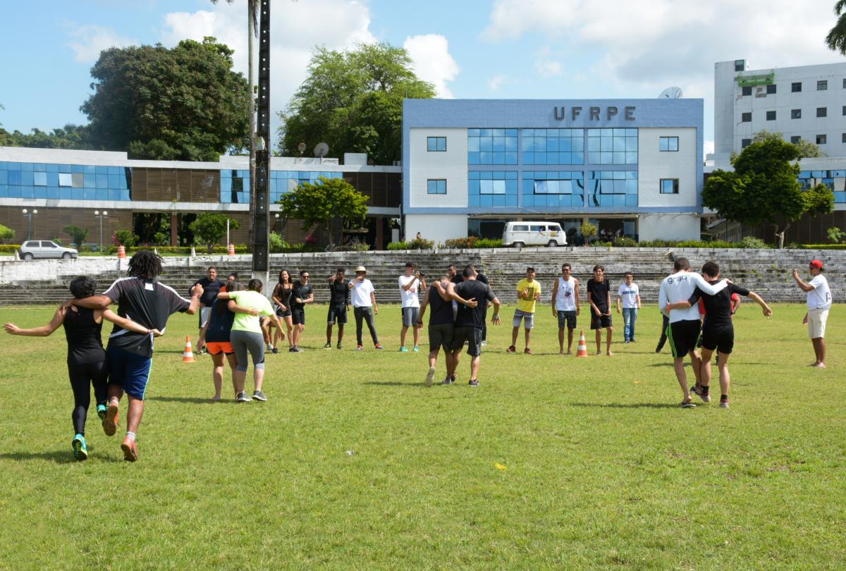 Estudantes com pernas amarradas correm em dupla. Prédio da UFRPE ao fundo