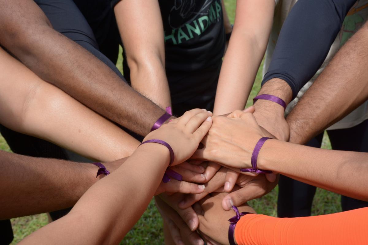 Braços dos integrantes de uma equipe juntos em saudação