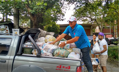 Foto de pessoas colocando alimentos numa picape
