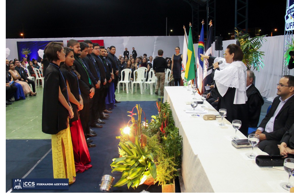 Reitora concede a o grau aos estudantes, estendendo as mão sobre os representantes de cada curso