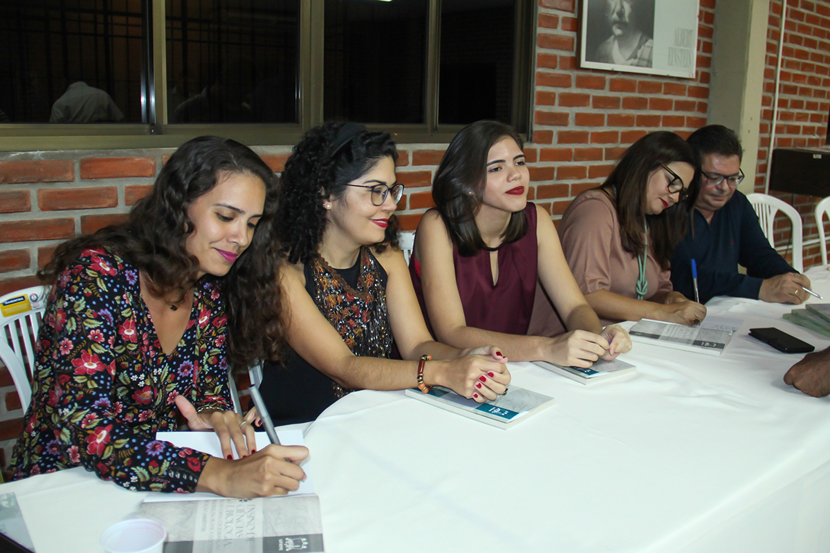 Autores assinando livros e fazendo dedicatórias