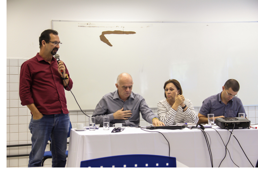 Diretor da UAG, Airon Melo, fala ao microfone. Reitora da UFRPE, reitor da UFCA e diretor administrativo da UAG sentados à mesa