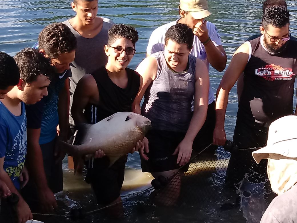 Alunos da Engenharia de pesca segurando peixes na estação de aquicultura