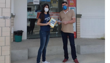 estudante entregando cartilha a funcionária do hospital