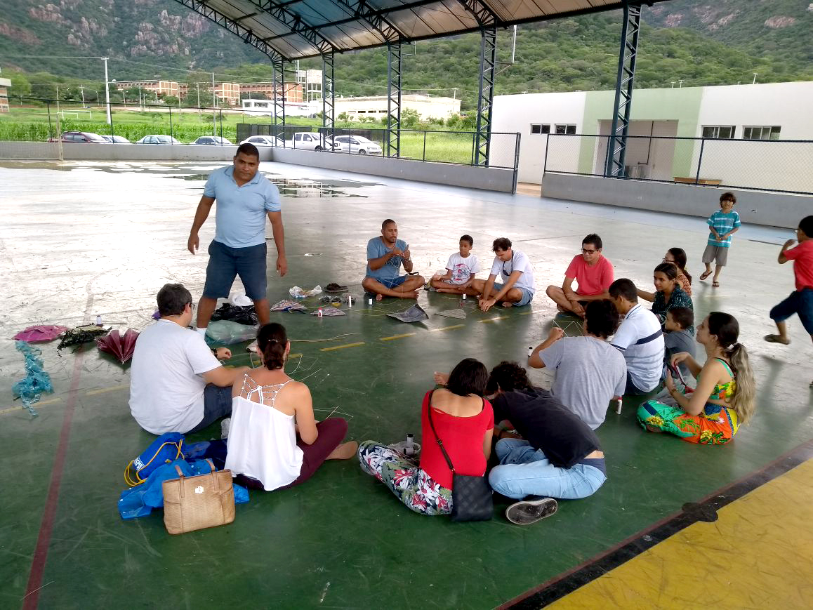 grupo sentado na quadra esportiva fazendo pipas